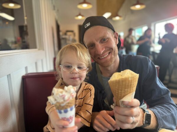 Dad and young child clinking ice cream cones together inside a shop on Camano Island