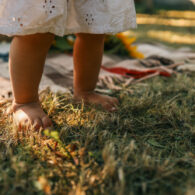 Little child walking on green grass outdoors, closeup.