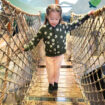 Little girl crossing a rope bridge at the Zoomazium indoor play area at Woodland Park Zoo in Seattle