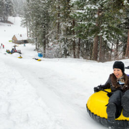 Woman in a tub at the top of the tubing hill smiles as she's about to go down